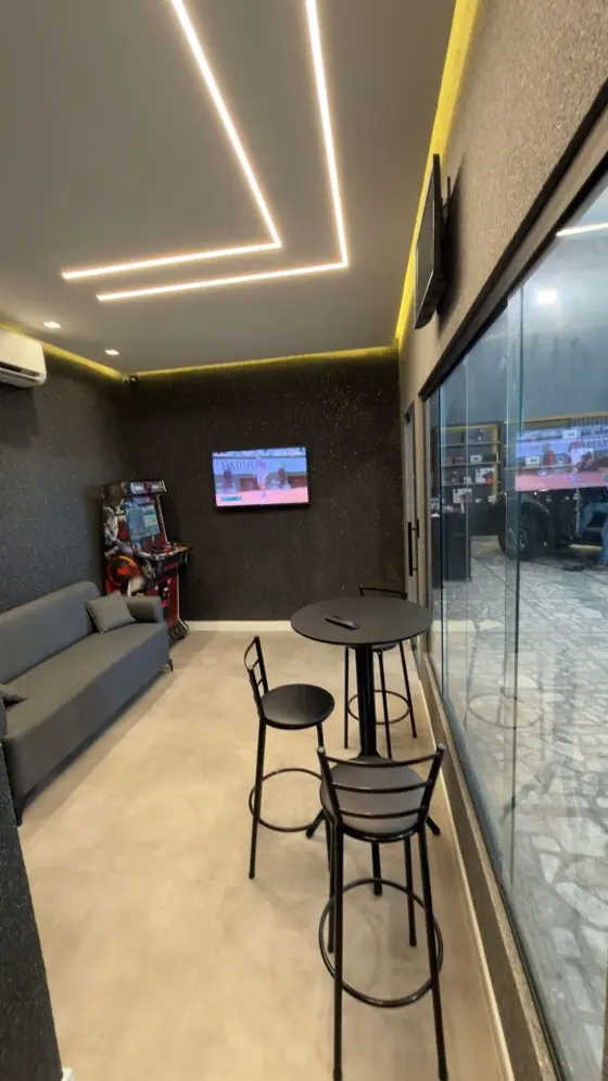 Espaço de espera da loja, com balcão e TV